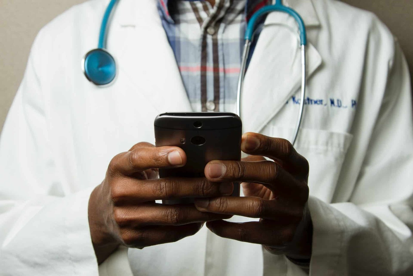 A doctor holding his phone and checking messages from his patients. 