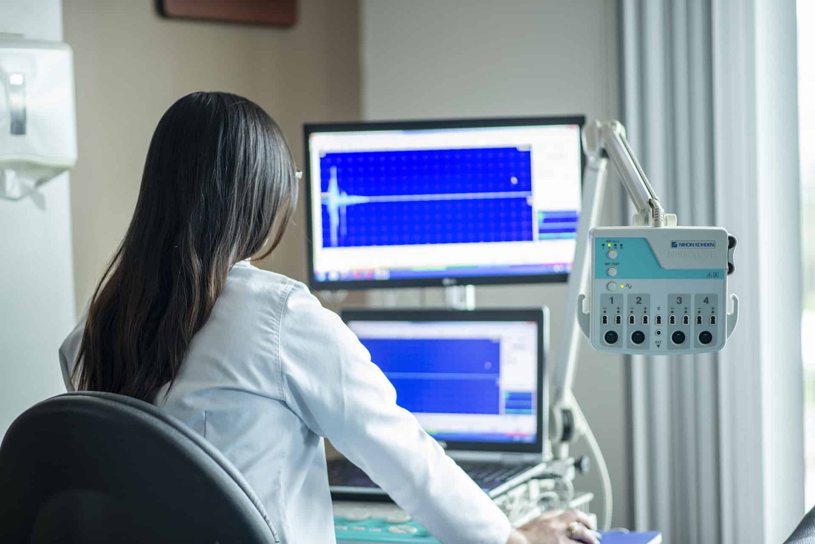 A doctor looking at a double-screened computer. 