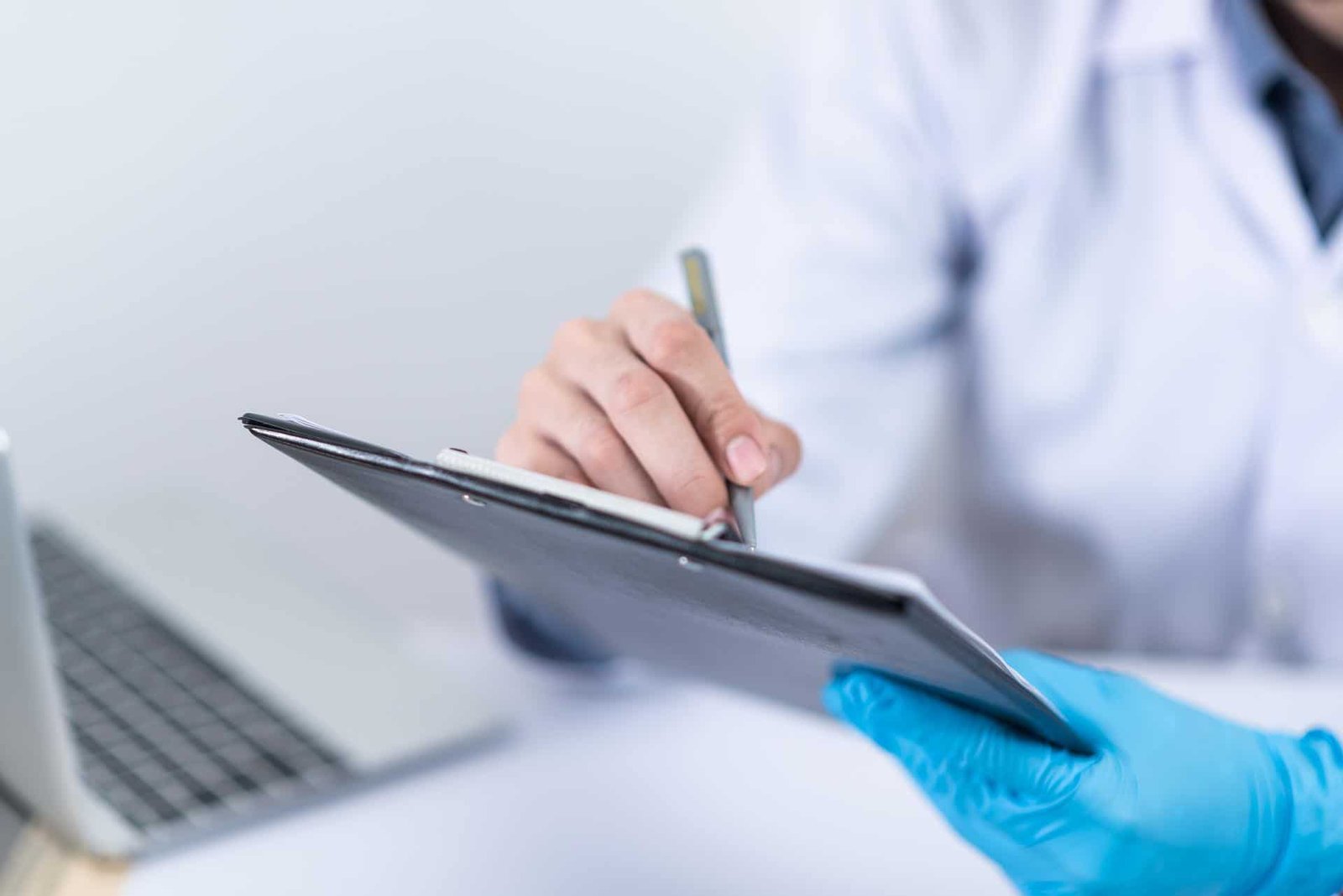 A doctor writing information down on a clipboard. 