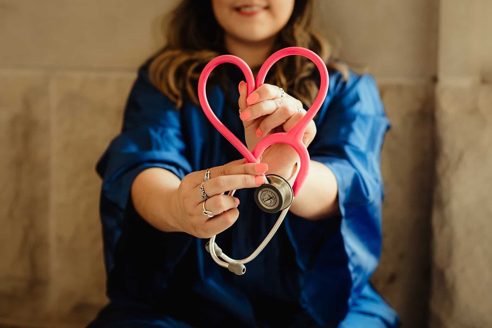 A nurse twisting a stethoscope into a heart. 